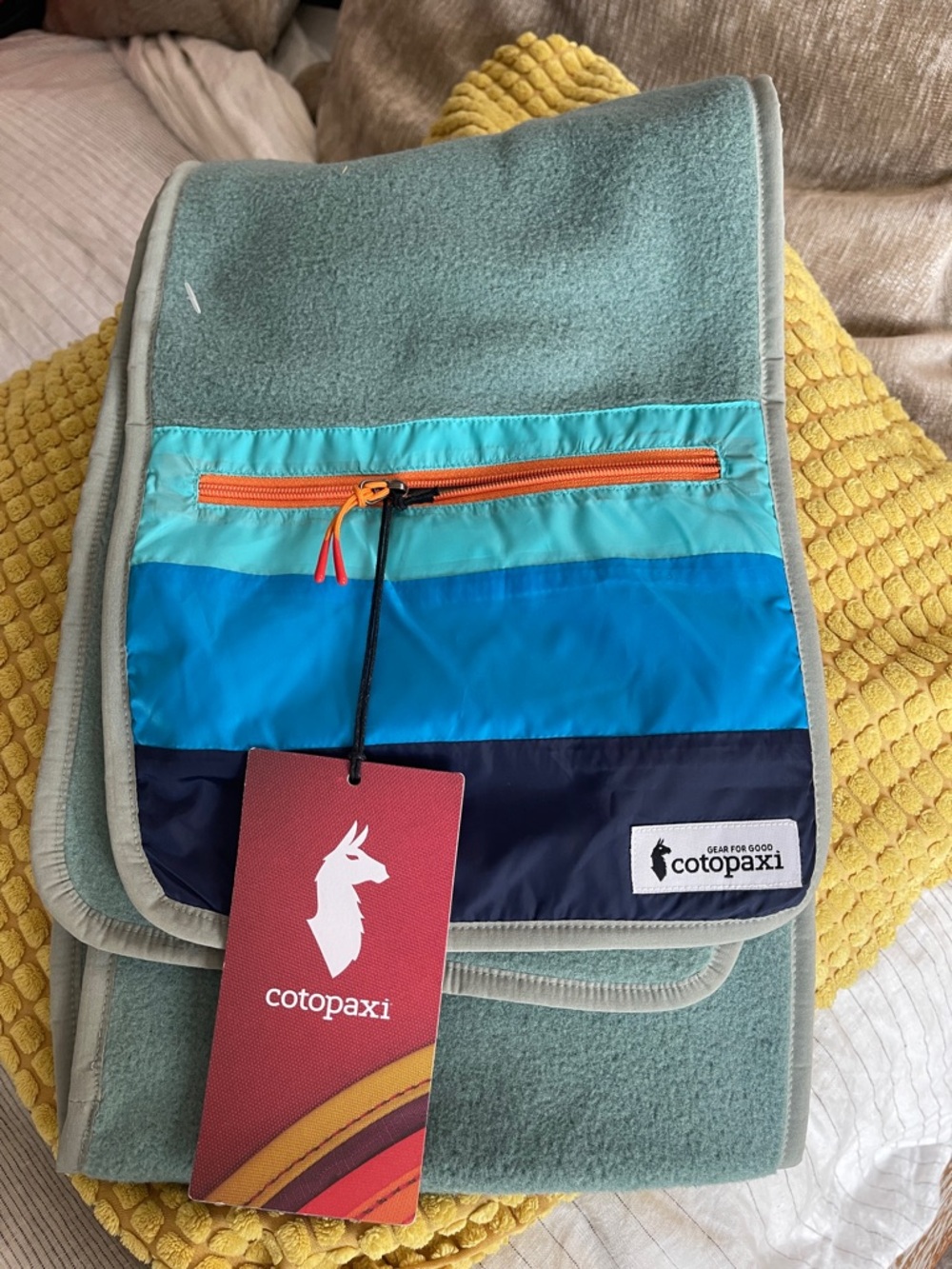 cotopaxi teal bag with blue and navy stripes and orange zipper